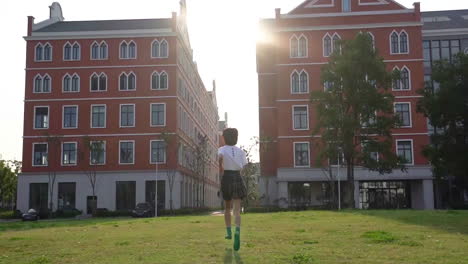 beautiful teenage girl students run towards the school building, schoolgirl is late against blue sky and sun