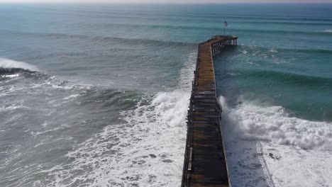 aerial over huge waves rolling in over a california pier in ventura california during a big winter storm suggests global warming and sea level rise or tsunami 8