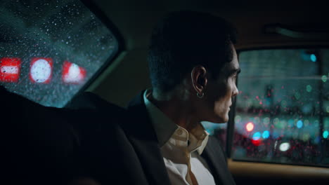 el pasajero del coche mirando por la ventana de la noche en primer plano. hombre perforado mirando fijamente la calle lluviosa