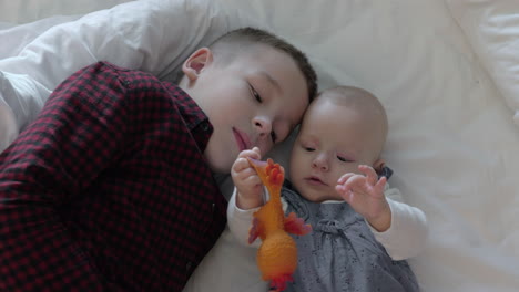 brother and sister lying on a bed and playing