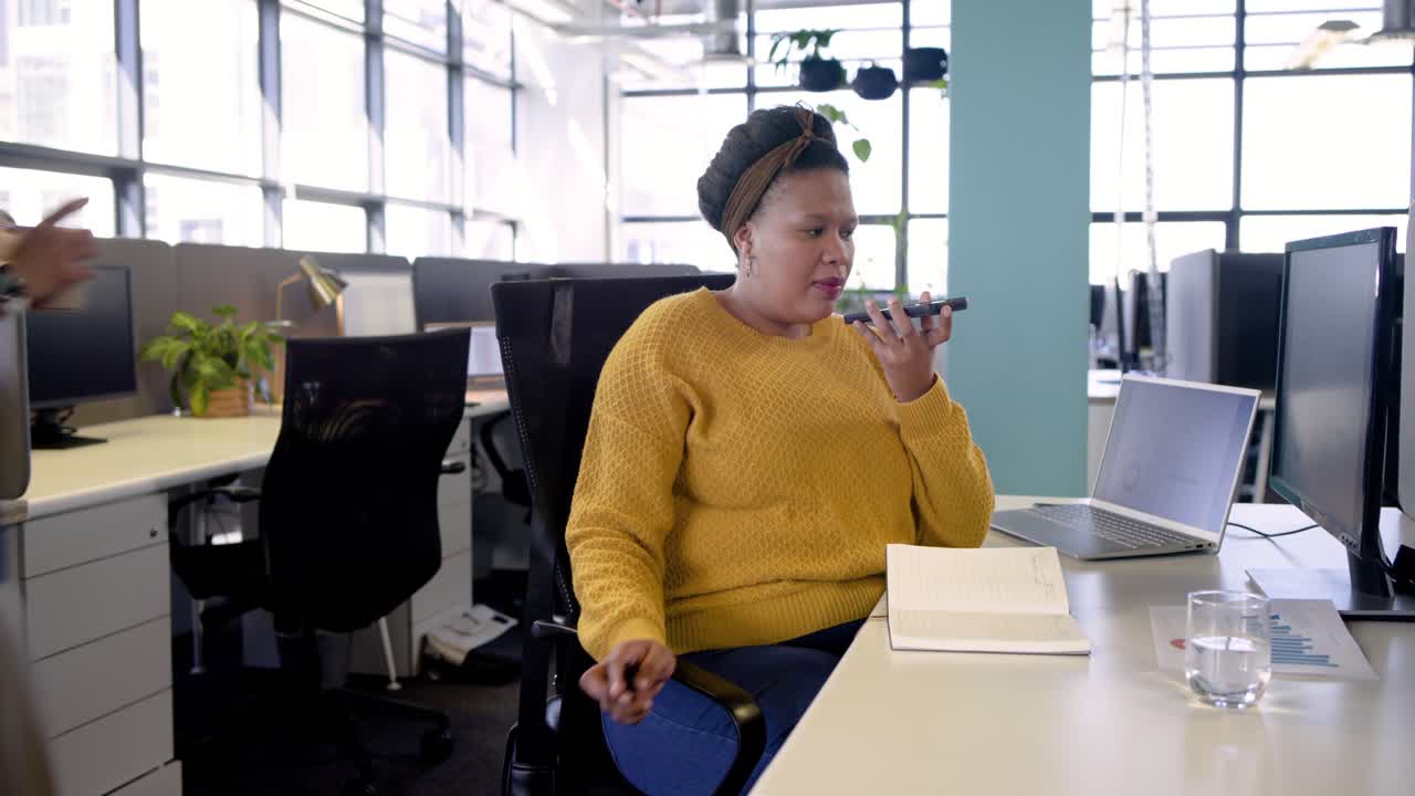 Funcionário afro-americano de escritório atendendo uma chamada no viva-voz, analisando gráficos, espaço para texto