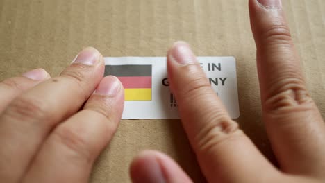 hands applying made in germany flag label on a shipping box with product premium quality barcode