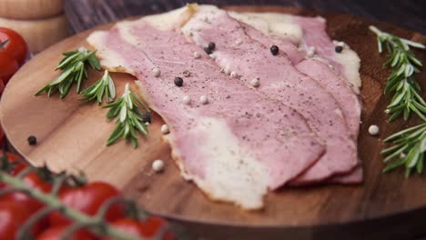 tocino en rebanadas en tabla de madera con hierbas y especias