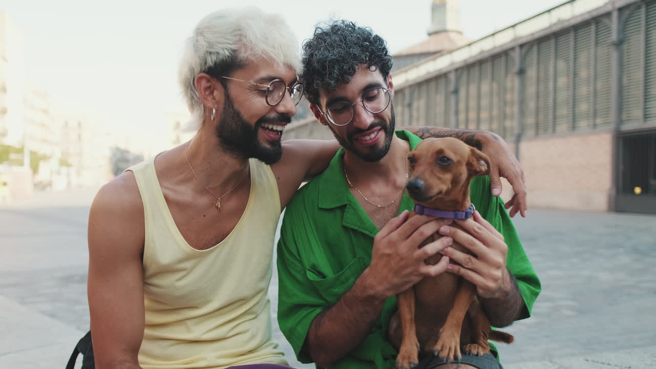 Pareja gay feliz abrazando y acariciando a su perro al aire libre