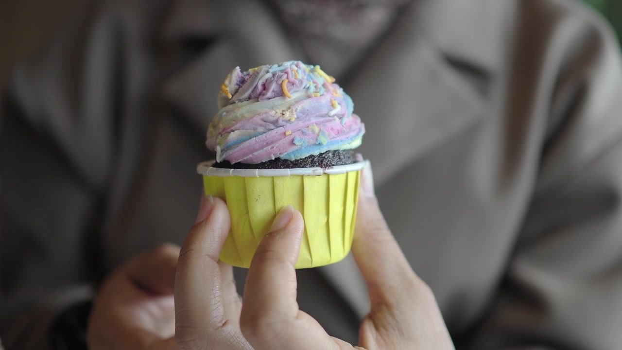 Persona che tiene un cupcake glassato e colorato