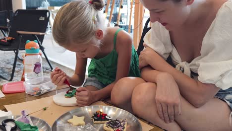 mother and daughter decorating halloween cookies