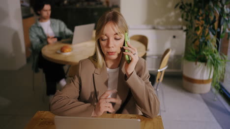 woman on a phone call while working on a laptop
