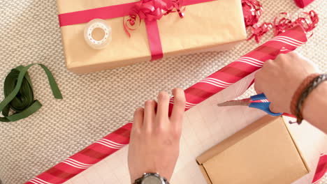 biracial man wrapping christmas present in decorative paper, slow motion