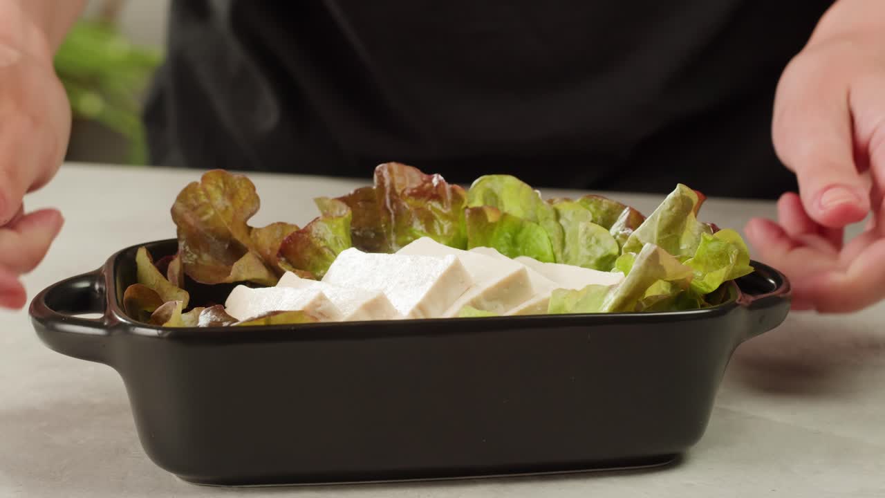 Fried tofu with sesame seeds and spices on cast iron pan, cooking japanese salad. Healthy ingredient for cooking vegan vegetarian diet food. Roasted tofu over black background.