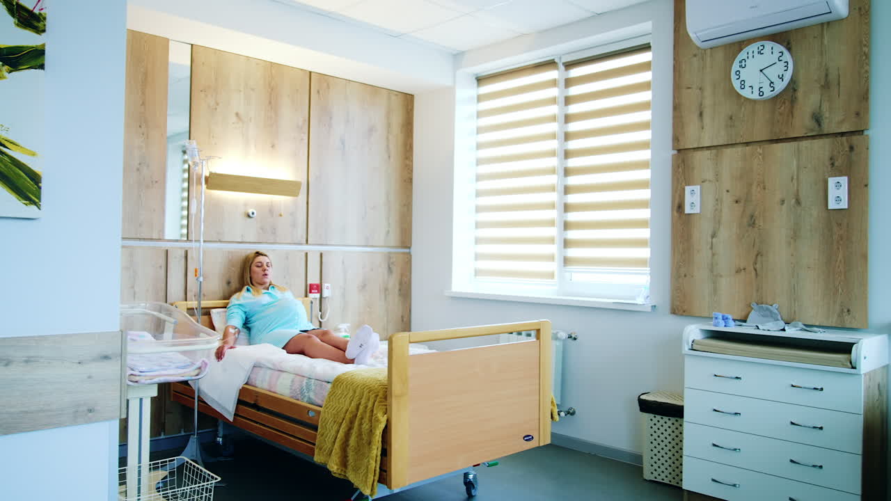 Big light comfortable ward in the maternity hospital. Pregnant lady lies on the bed under the drop counter. Preparation before childbirth.