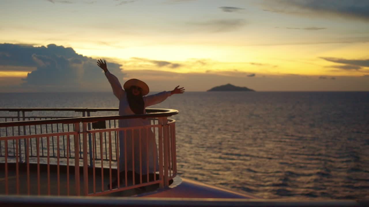feliz mujer musulmana asiática bailando mientras disfruta de la puesta de sol desde la cubierta superior del crucero