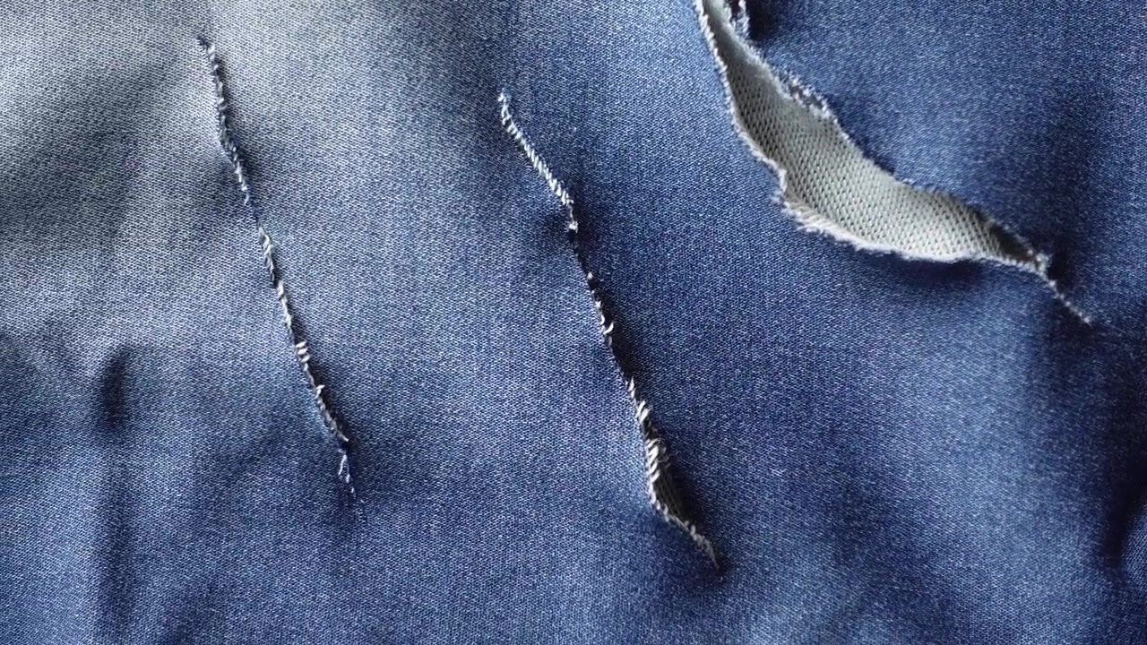 Close-up of Ripped Blue Denim Fabric Texture