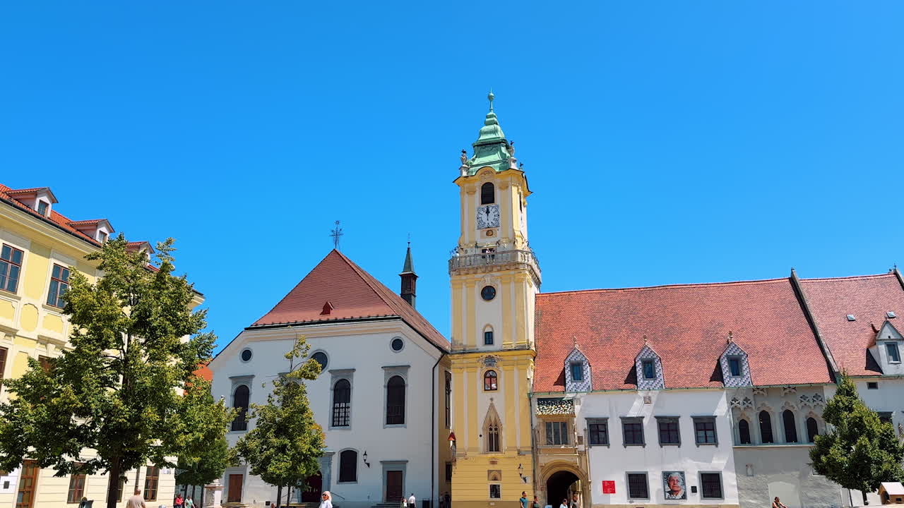 Beautiful historical buildings and tower clock in the square of Bratislava, Slovakia. Old town of the city on sunny day