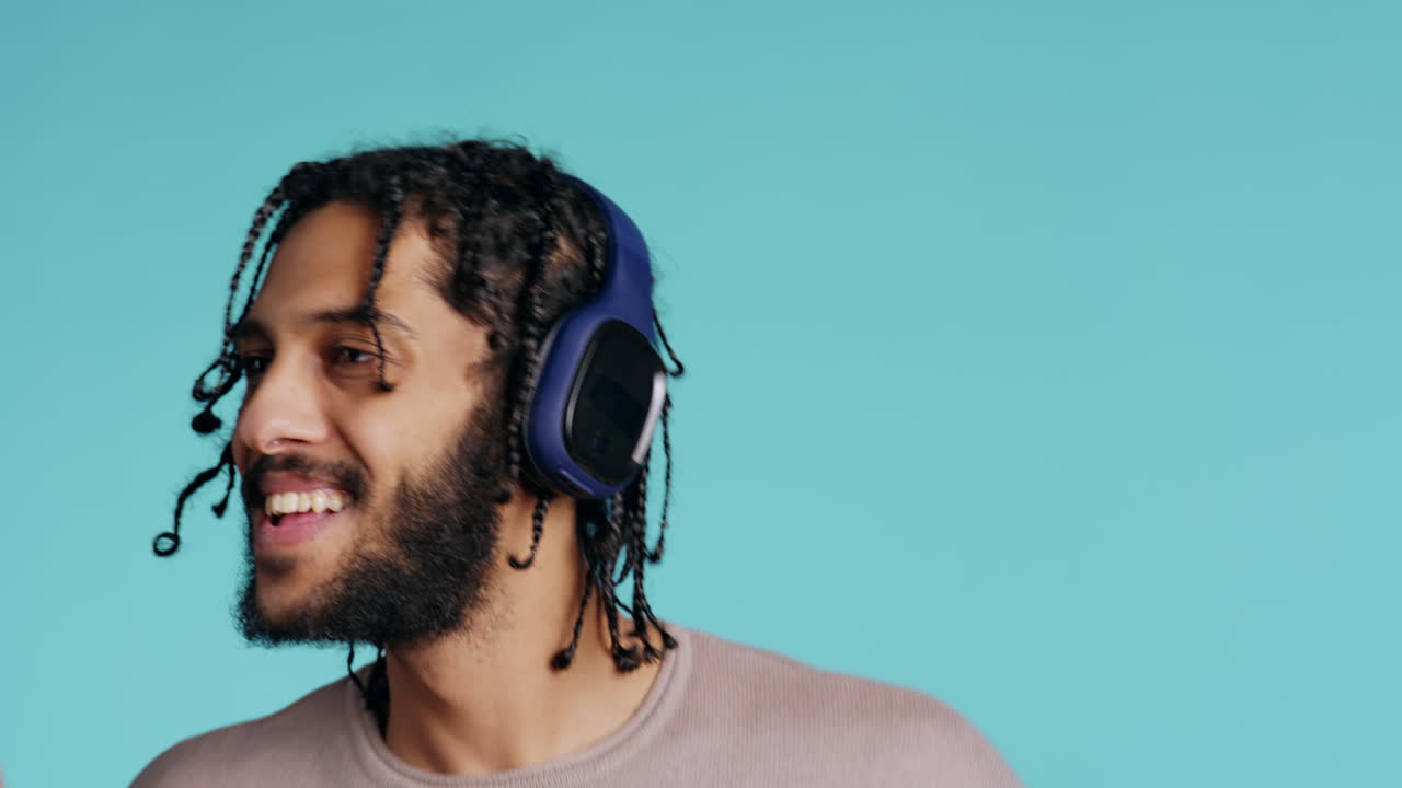 Uomo gioioso che ascolta musica, si diverte e balla, su sfondo in studio.