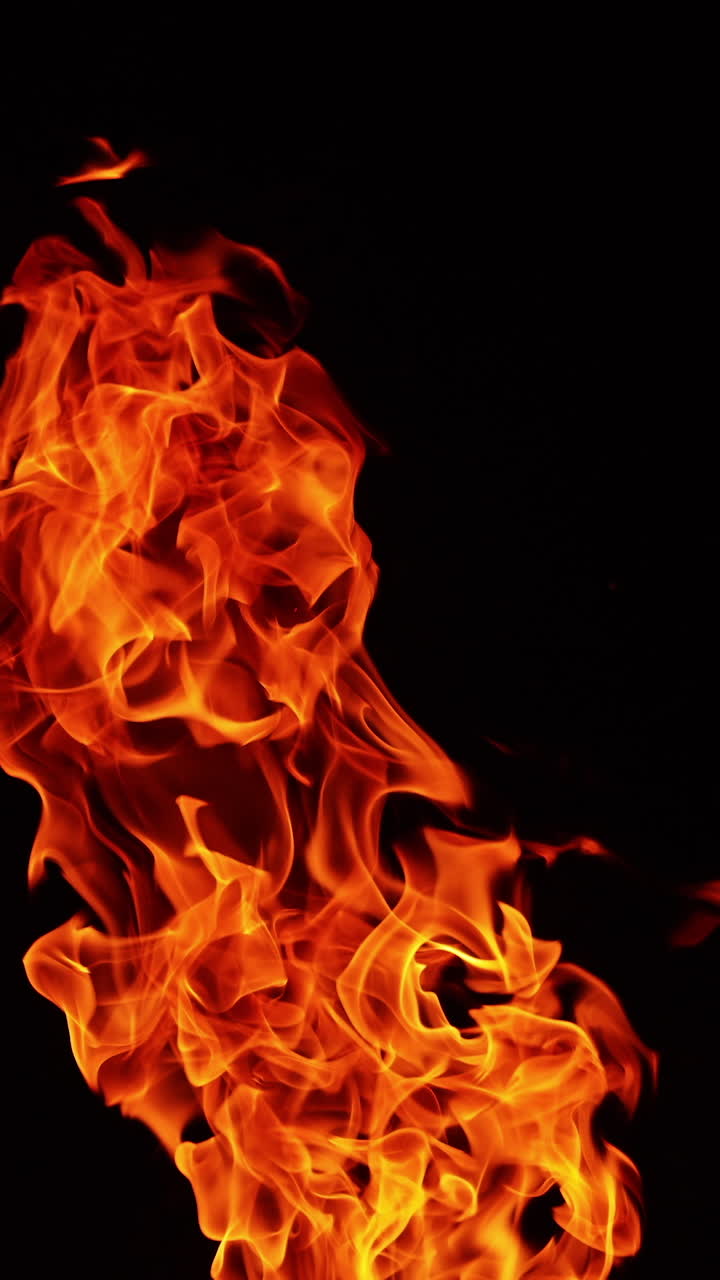 Tongues of campfire flames striving up into the air. Top part of the bonfire isolated at black backdrop. Vertical video