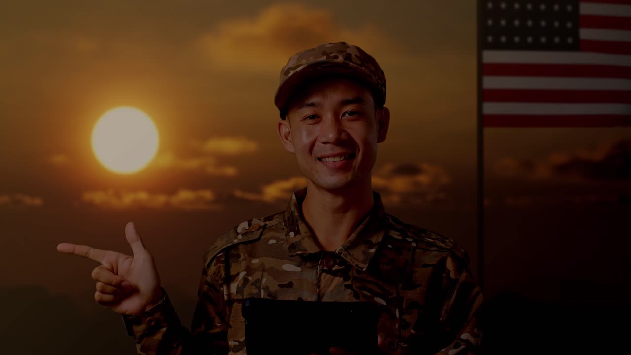 태블릿을 사용하고 을 가리키는 아시아 남성 군인의 클로즈업 미국 발을 들고 서있는 동안, 해가 지는 시간