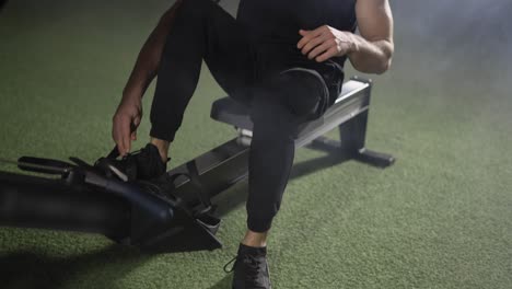 Bearded-sportsman-works-out-in-gym-with-rowing-machine,-close-up