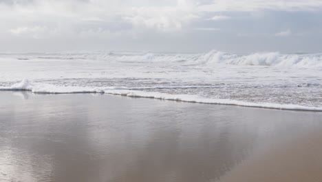 waves crashing down on the beach and into the caméra.