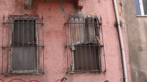 closeup de dos ventanas con barras de hierro en un exterior de edificio rosa