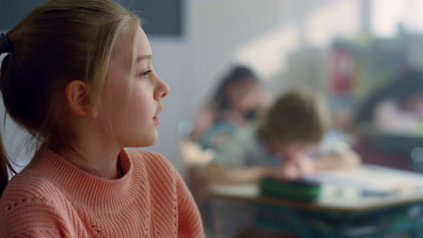 girl sitting at desk in classroom. smart student raising hand to ask question