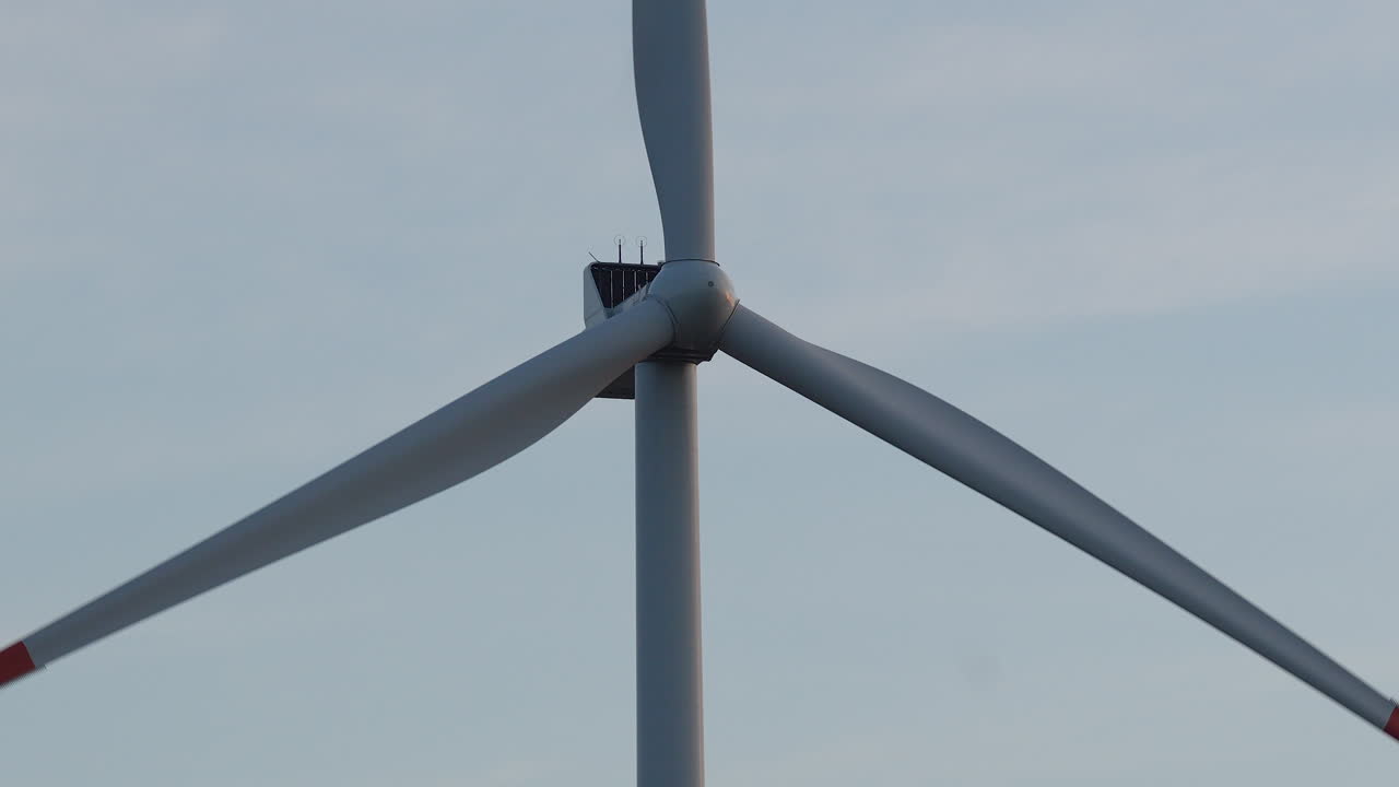 은 하늘을 배경으로 회전하는 풍력 터빈 블레이드의 클로즈업, 평온한 환경에서 청정 에너지 기술을 강조합니다.
