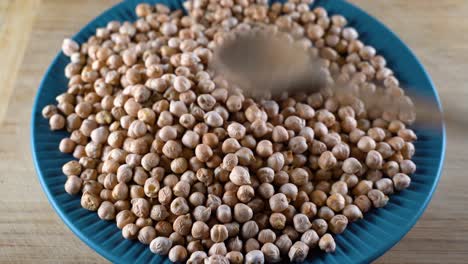 Scattered Turkish chickpeas are sorted with a wooden spoon. High-protein legumes, beans and lentils for a healthy diet.