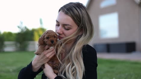 mujer rubia sosteniendo y abrazando a un lindo cachorro goldendoodle