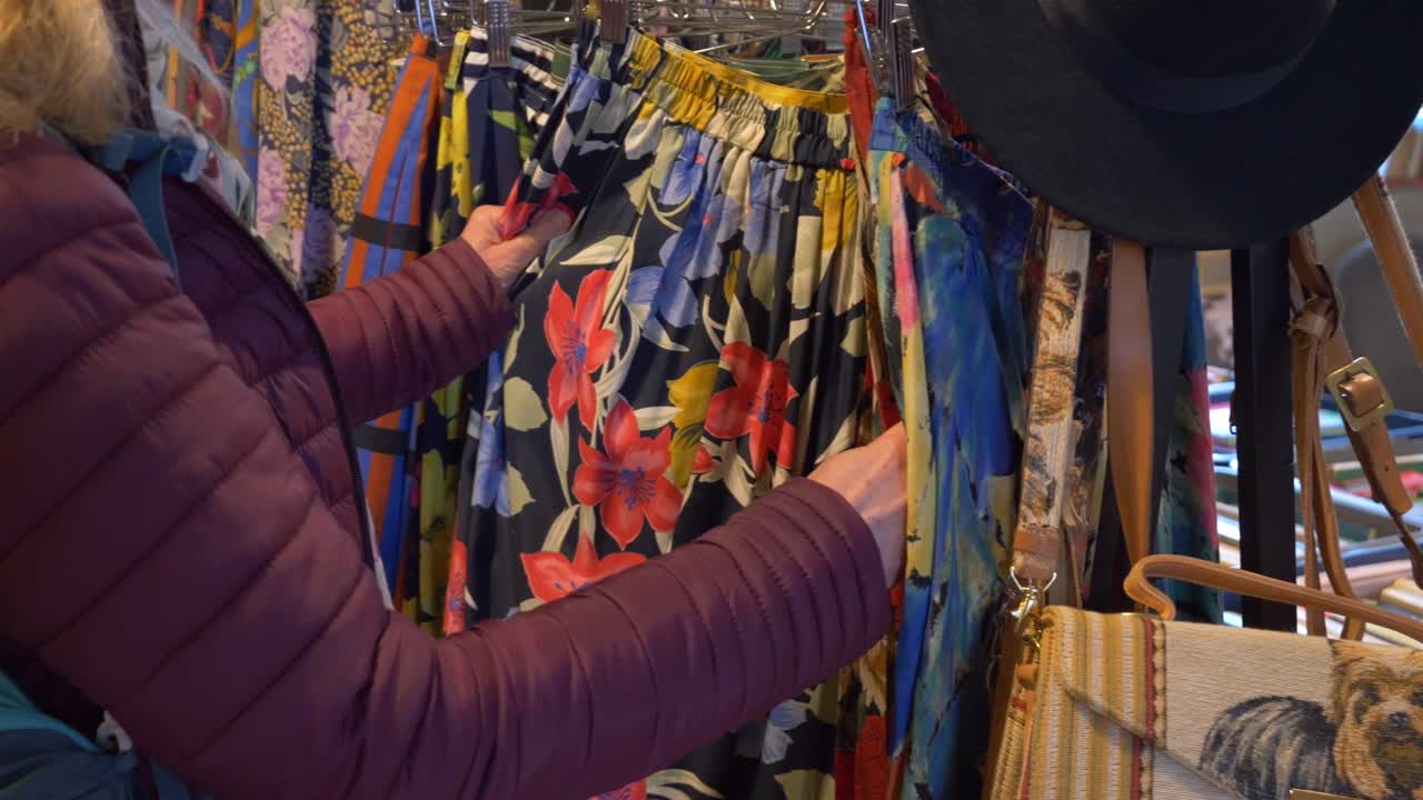 el cliente está mirando pantalones coloridos en un mercado de antigüedades