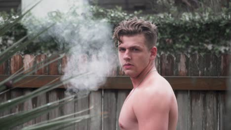 male model looking back at camera blowing smoke slow motion