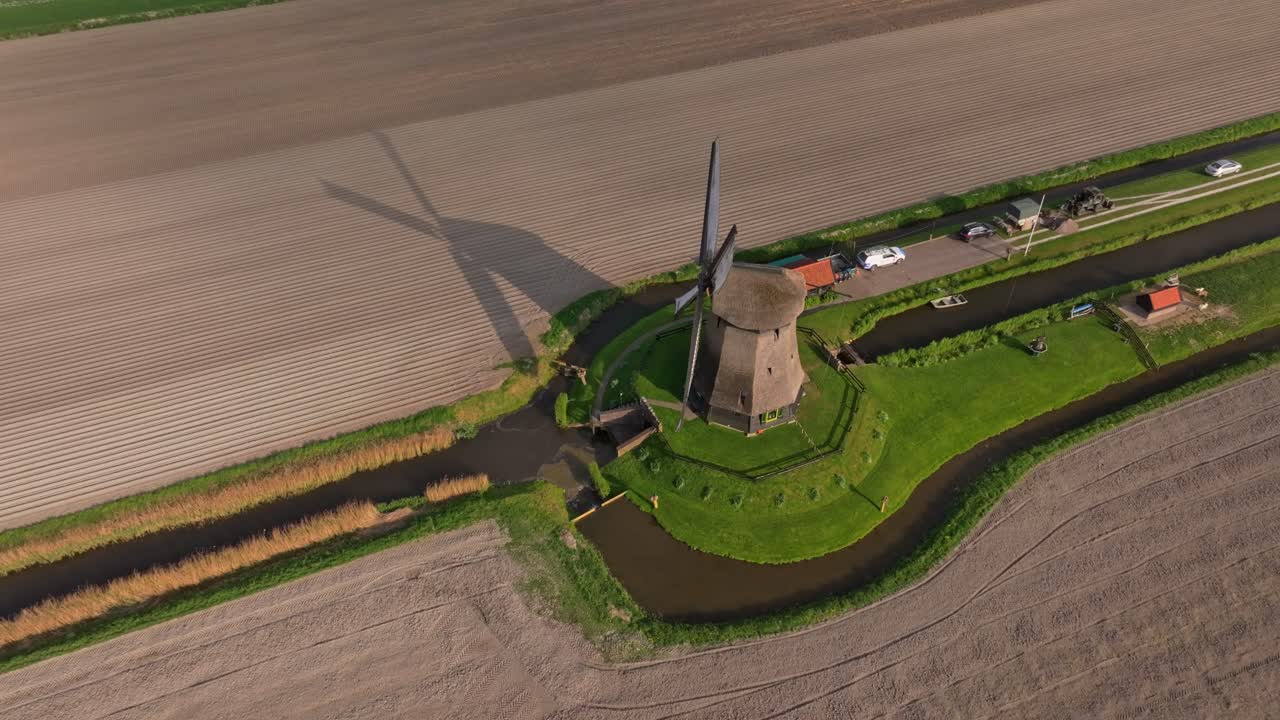 Pemandangan udara kincir angin yang berputar di antara ladang hijau di pedesaan Belanda.