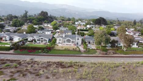 Drone-fly-over-housing-with-parking-lot-along-train-track