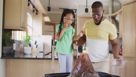 happy african american father and daughter doing science experiments with artificial volcano