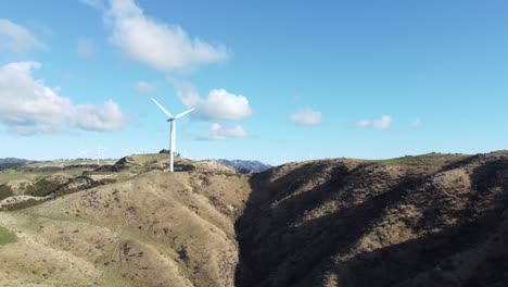 una toma aérea estática de una turbina eólica con un parque eólico en el fondo