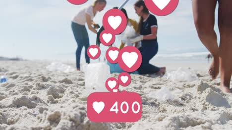 Animation-of-social-media-heart-icons-over-diverse-volunteer-group-picking-up-rubbish-from-beach