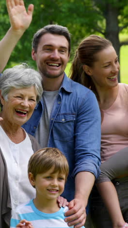 multi generation family posing and waving at camera in a park