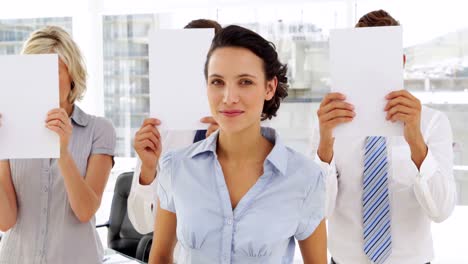 Cheerful-businesswoman-standing-in-front-of-colleagues-holding-paper