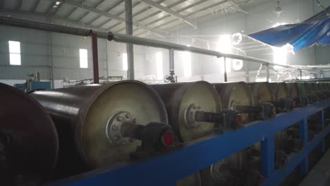 rows of large spinning drums inside textile factory in pakistan