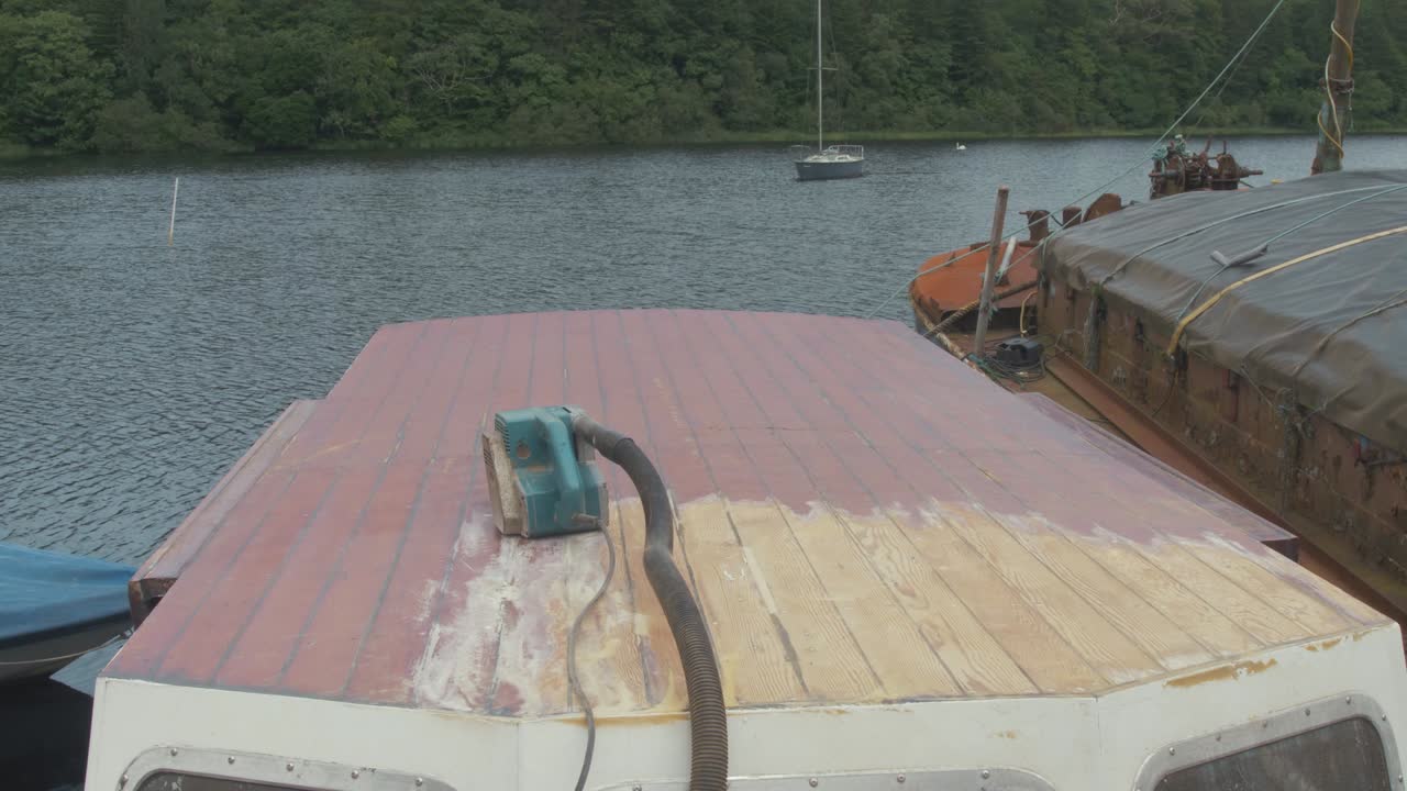 timelapse de un joven carpintero quitando barniz en el techo de la timonera de un barco de madera