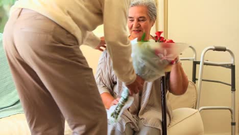 hombre maduro trayendo a su esposa un ramo de flores en el hospital