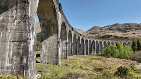 Glenfinnan-Viaduct-Railway-Bridge-in-Scottish-Highlands,-Sliding-Shot