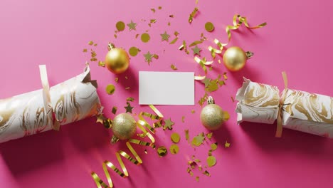 Video-of-pulled-cracker,-gold-streamers,-baubles-and-confetti-on-pink-background