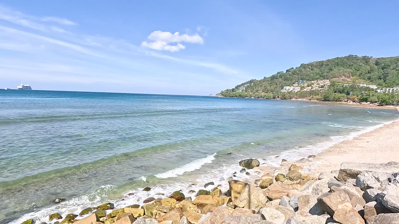 A serene coastal panorama with clear skies and gentle waves at Kalim Beach, captured in bright daylight with a steady camera