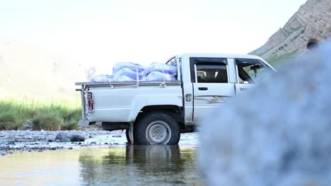 close up shot the jeep carrying numerous sacks of grains and other necessaries and supplies is stopped at stream of the river