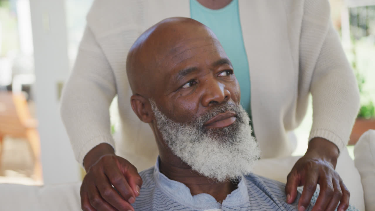 행복한 노인 아프리카계 미국인 커플이 슬로모션으로 거실에서 포옹하고 미소 짓고 있습니다.