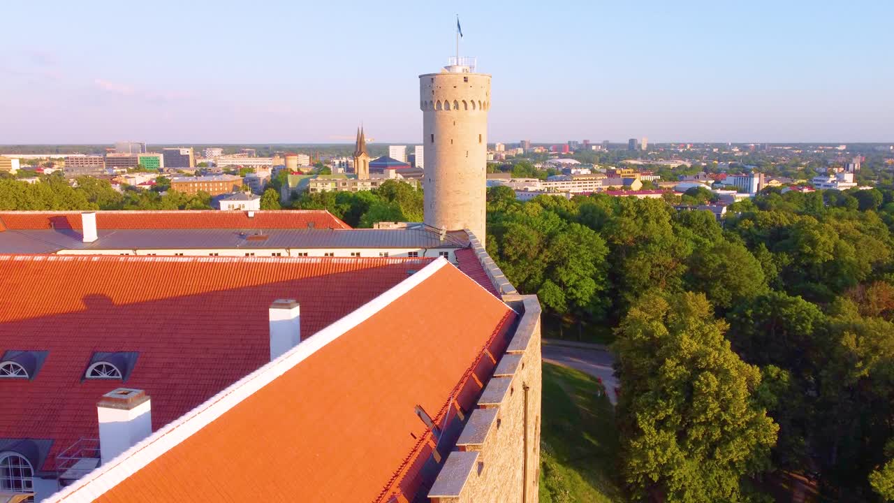 La città vecchia di Tallinn con tetti rossi, alberi verdi e un panorama storico al tramonto, vista aerea.