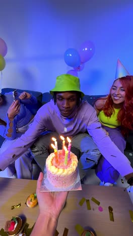 vertical video studio shot of gen z friends celebrating man's birthday with party cake and candles sitting on sofa 2