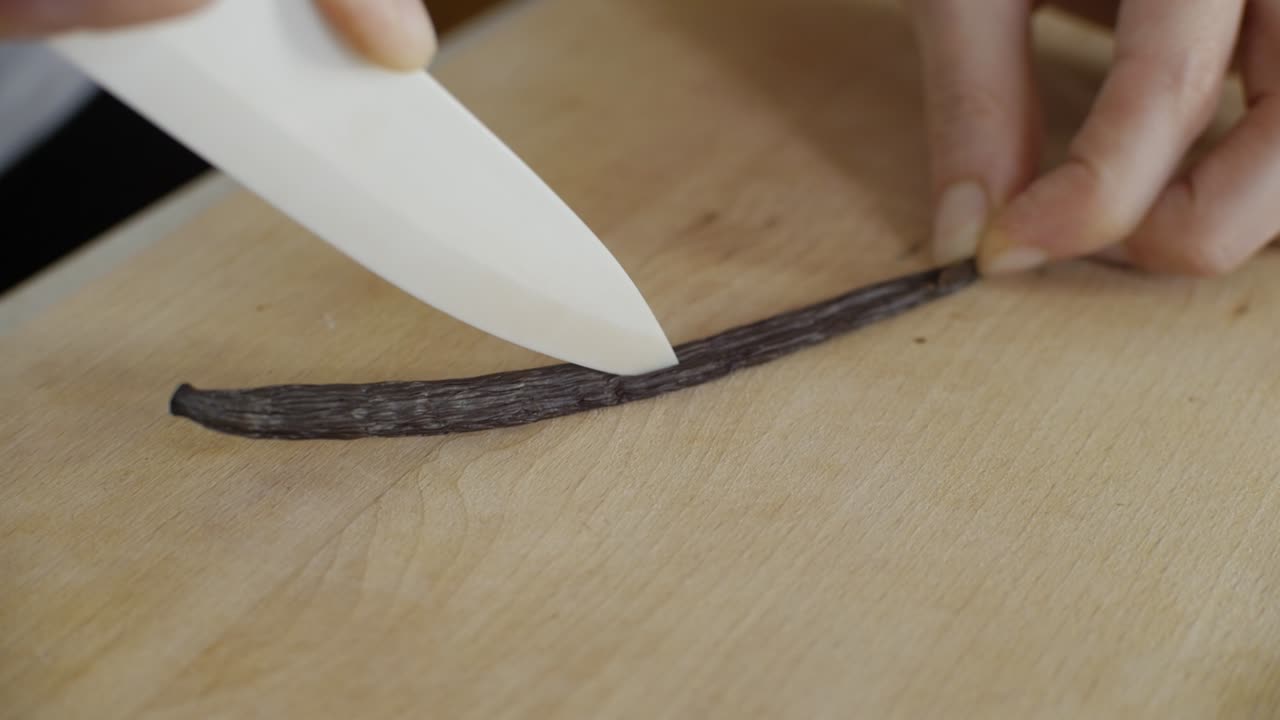 Cutting bourbon vanilla stick in half with knife