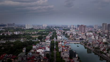 aerial tracking above a train passing through central hanoi, vietnam, with urban cityscape and cloudy sky