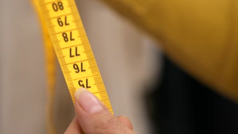 Sliding-yellow-tape-measure-through-womans-hands,-Slow-Motion-Closeup