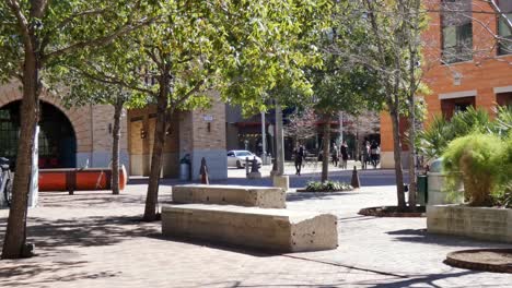 un hombre corriendo a través de un lugar de reunión de la plaza de un pequeño pueblo con árboles y edificios